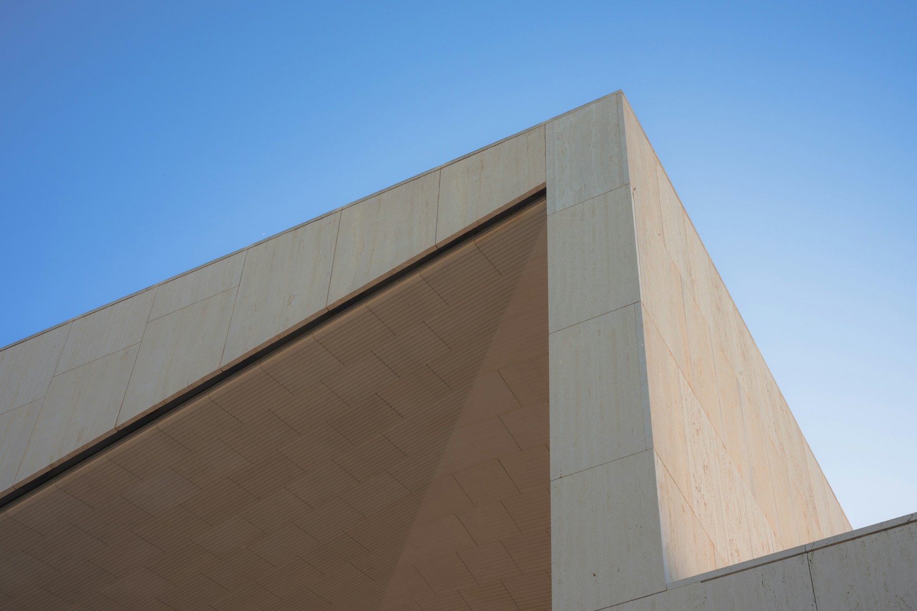 Sculptural pale stone architecture seen from below, opening toward the sky